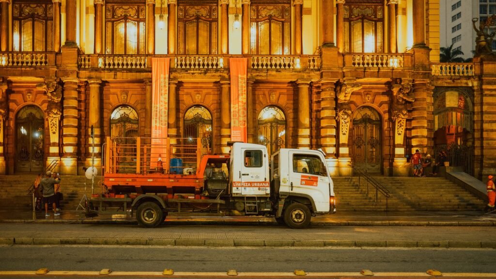 Front view of the Municipal Theatre in São Paulo, Brazil, illuminated at night with an urban cleaning truck parked in front.
